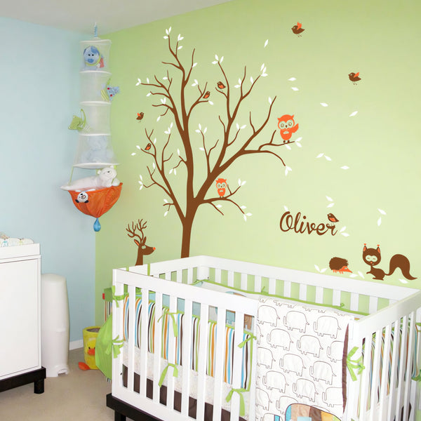 Tree wall sticker with animals and the name of a loved one in a nursery with a crib.