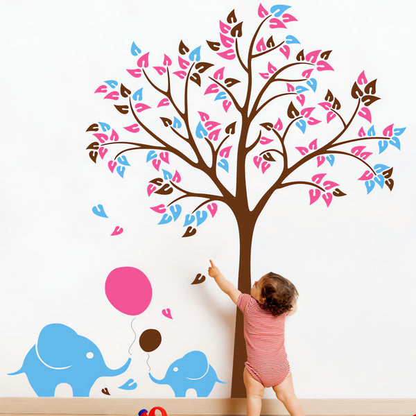 Tree wall sticker with ballons and a baby elephant in a nursery with a baby playing.