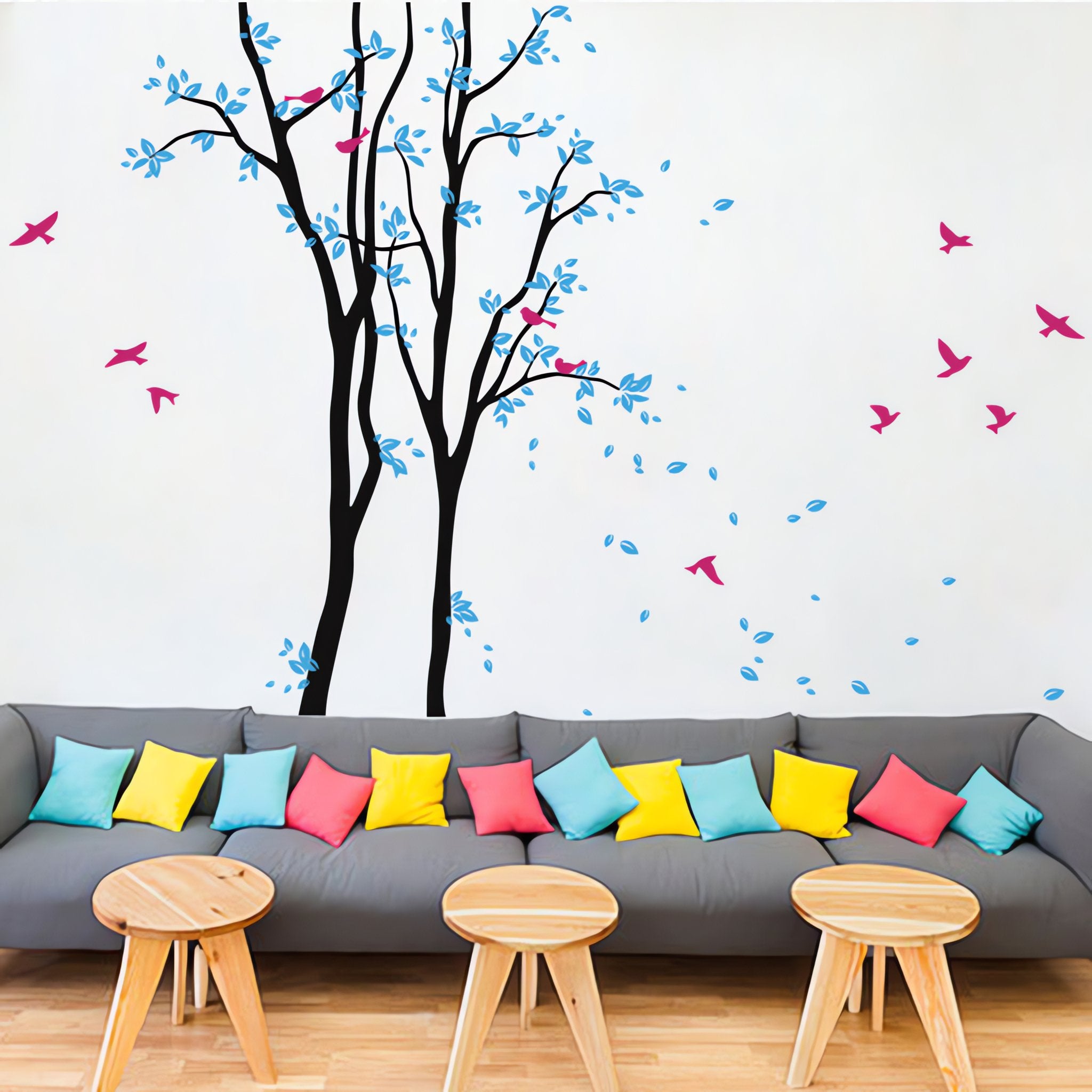 Tree wall sticker with birds in a living room with a long sofa with many cushions.