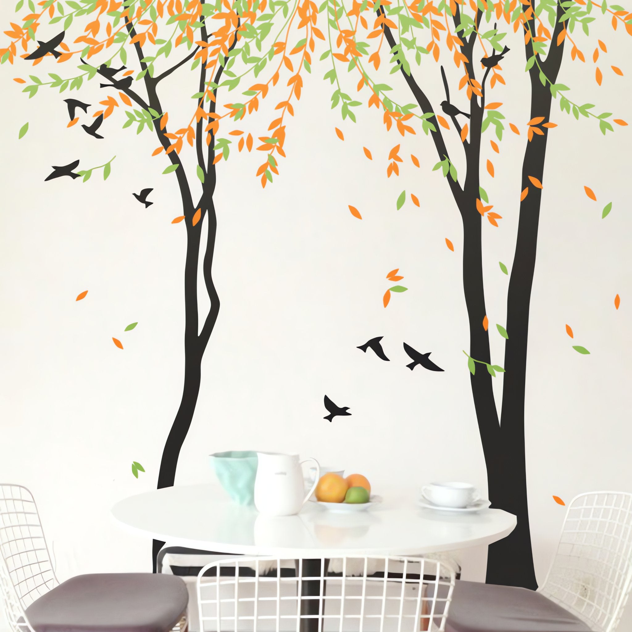 Tree wall sticker with birds and falling leaves in a room with a small dining table and 2 chairs.