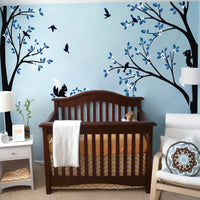 Tree wall sticker with birds and squirrels in a nursery with a crib, a nightstand and a chair.