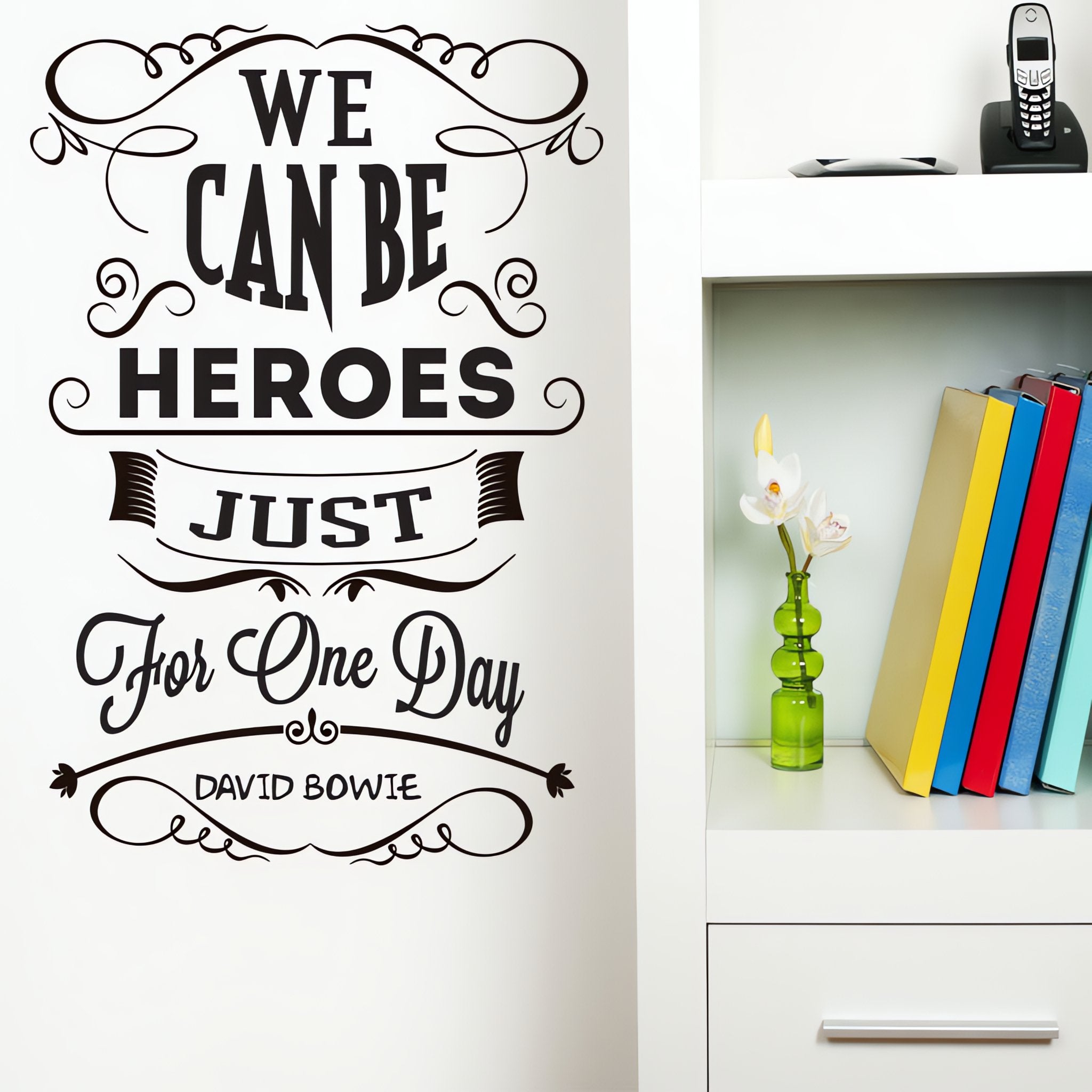 Wall quote sticker with text "We Can Be Heroes Just For One Day" by David Bowie next to a shelf.