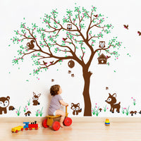 Tree wall sticker with animals in a nursery with a baby playing and various toys.