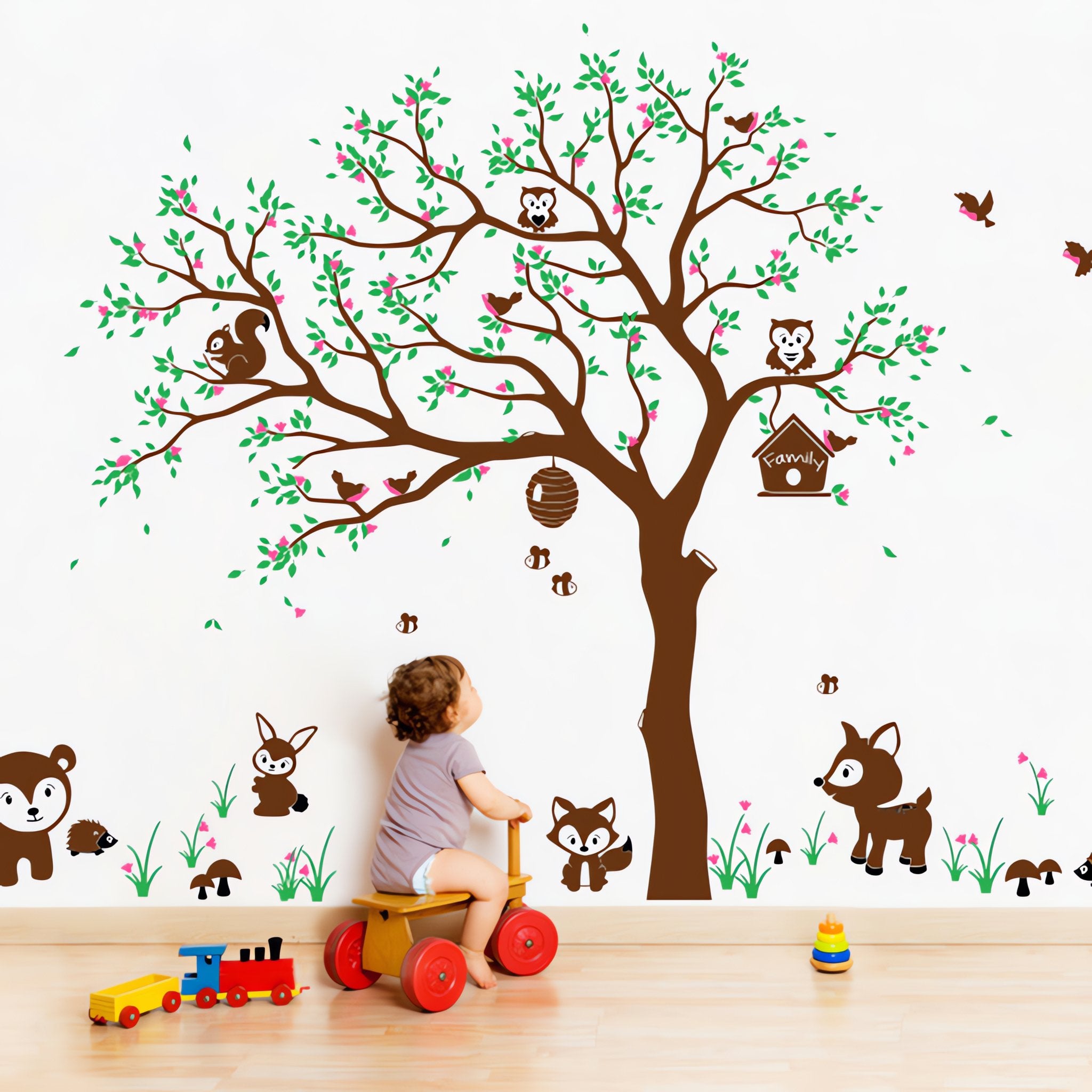 Tree wall sticker with animals in a nursery with a baby playing and various toys.
