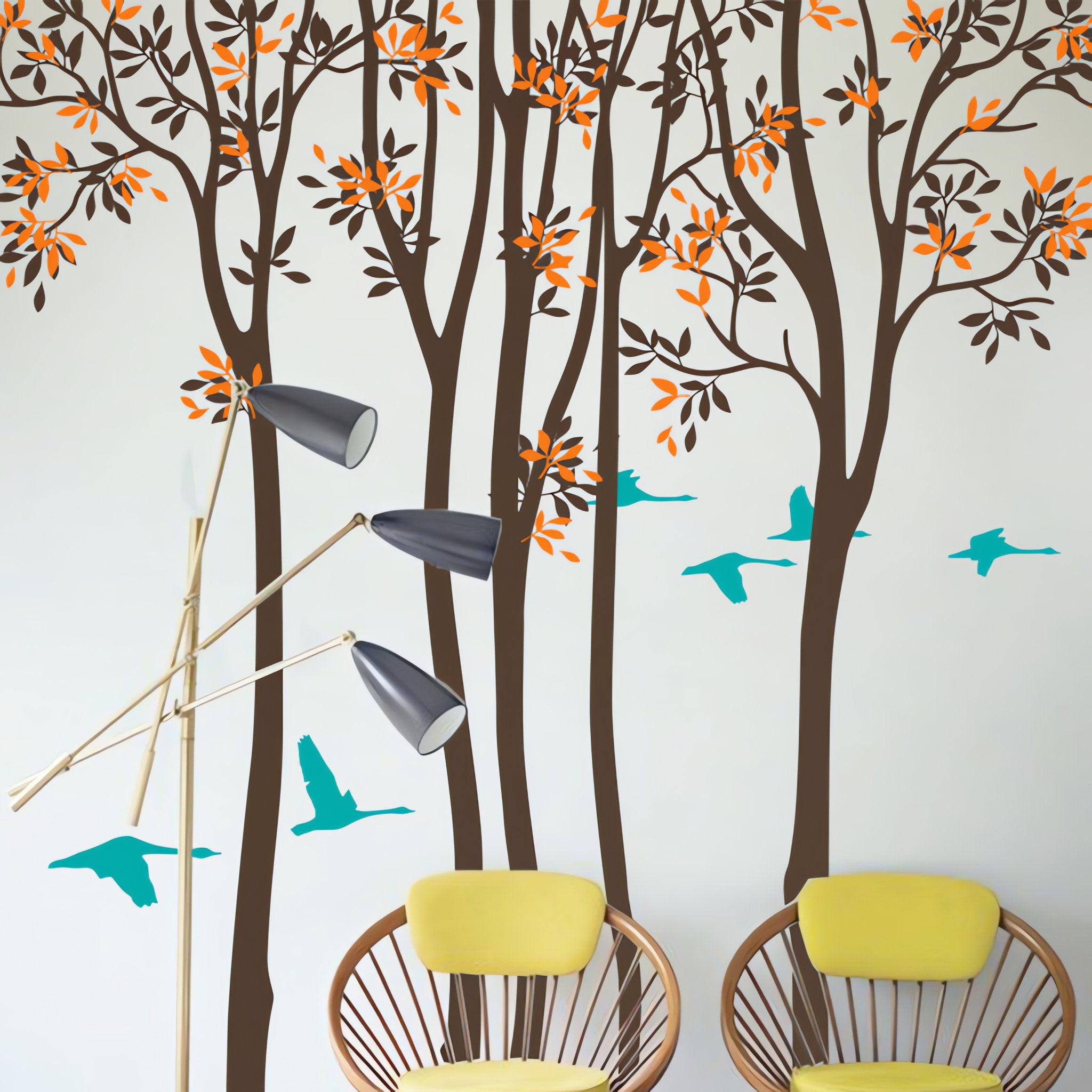 Tree wall sticker with tall thin trees and birds in a room with 2 chairs.