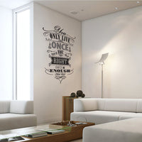 Wall quote sticker with text "You Only Live Once But If You Do It Right Once Is Enough" in a brightly lit living room with a corner couch and more seating.